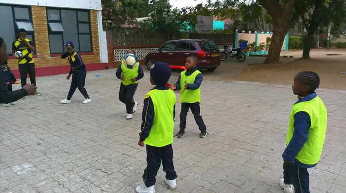 Learners playing soccer outdoors